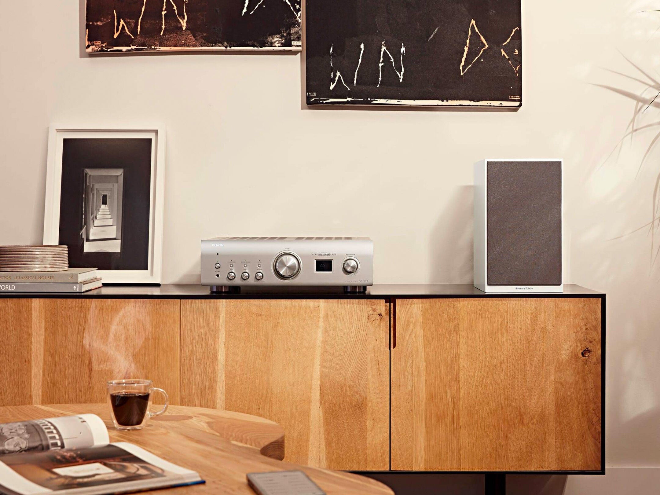 Amplificator Denon PMA-1700NE argintiu pe mobilier din lemn, cu butoane de control și afișaj central.