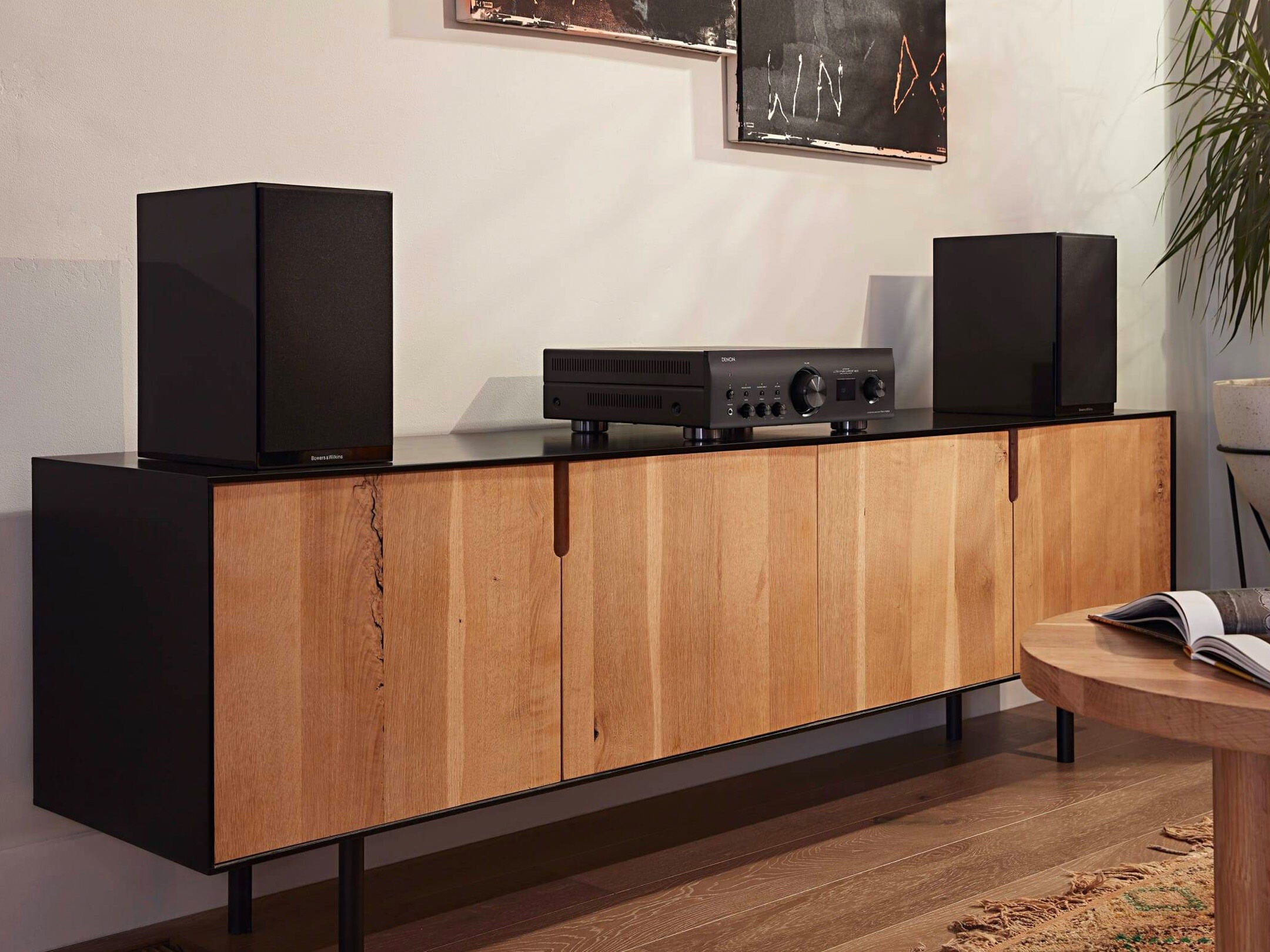 Amplificator Denon PMA-1700NE, vedere unghiulară, negru, plasat pe un dulap din lemn, alături de boxe negre.