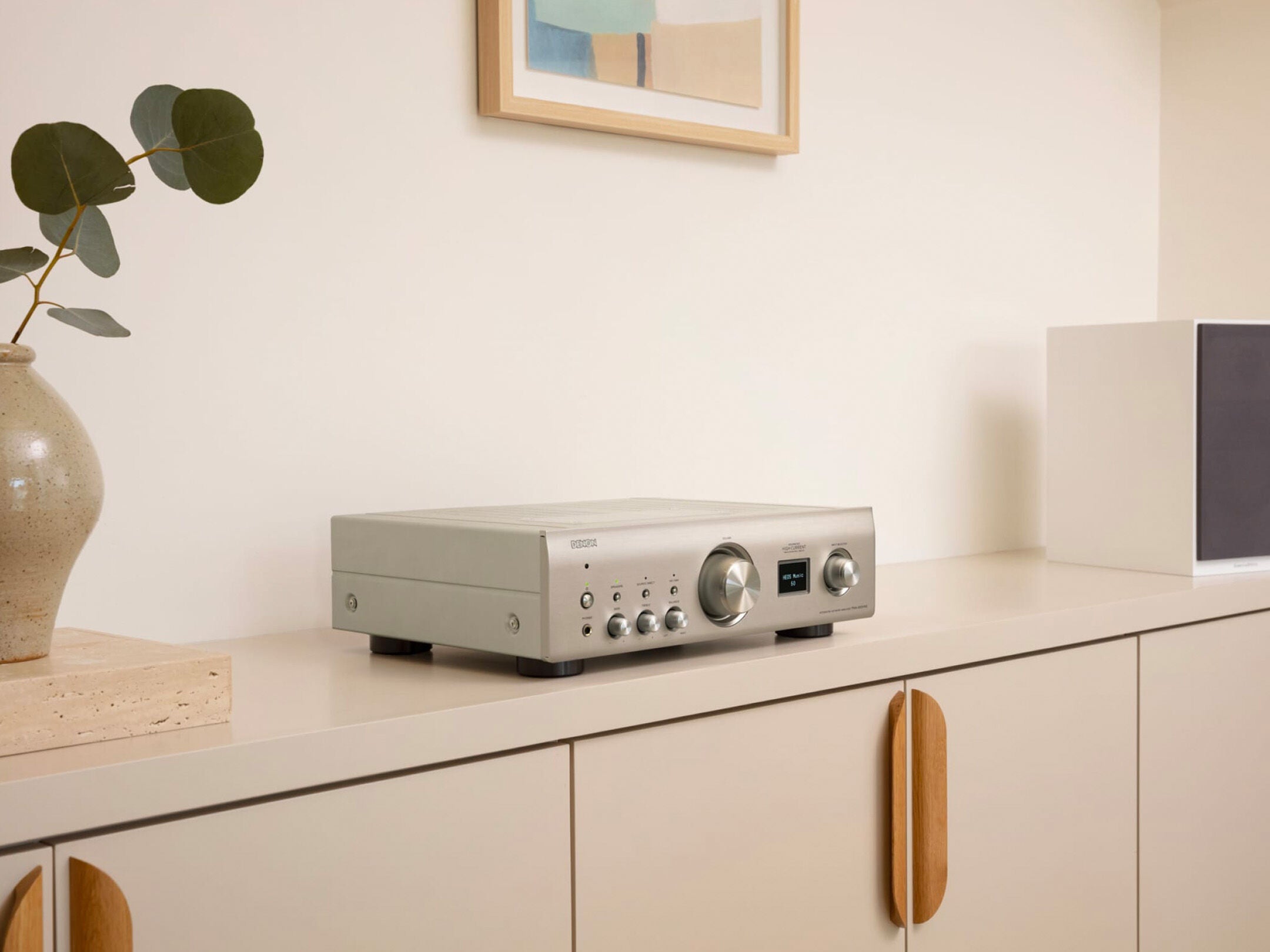 Denon PMA-900HNE Amplificator argintiu, vedere laterală, afișaj digital și butoane de control vizibile.