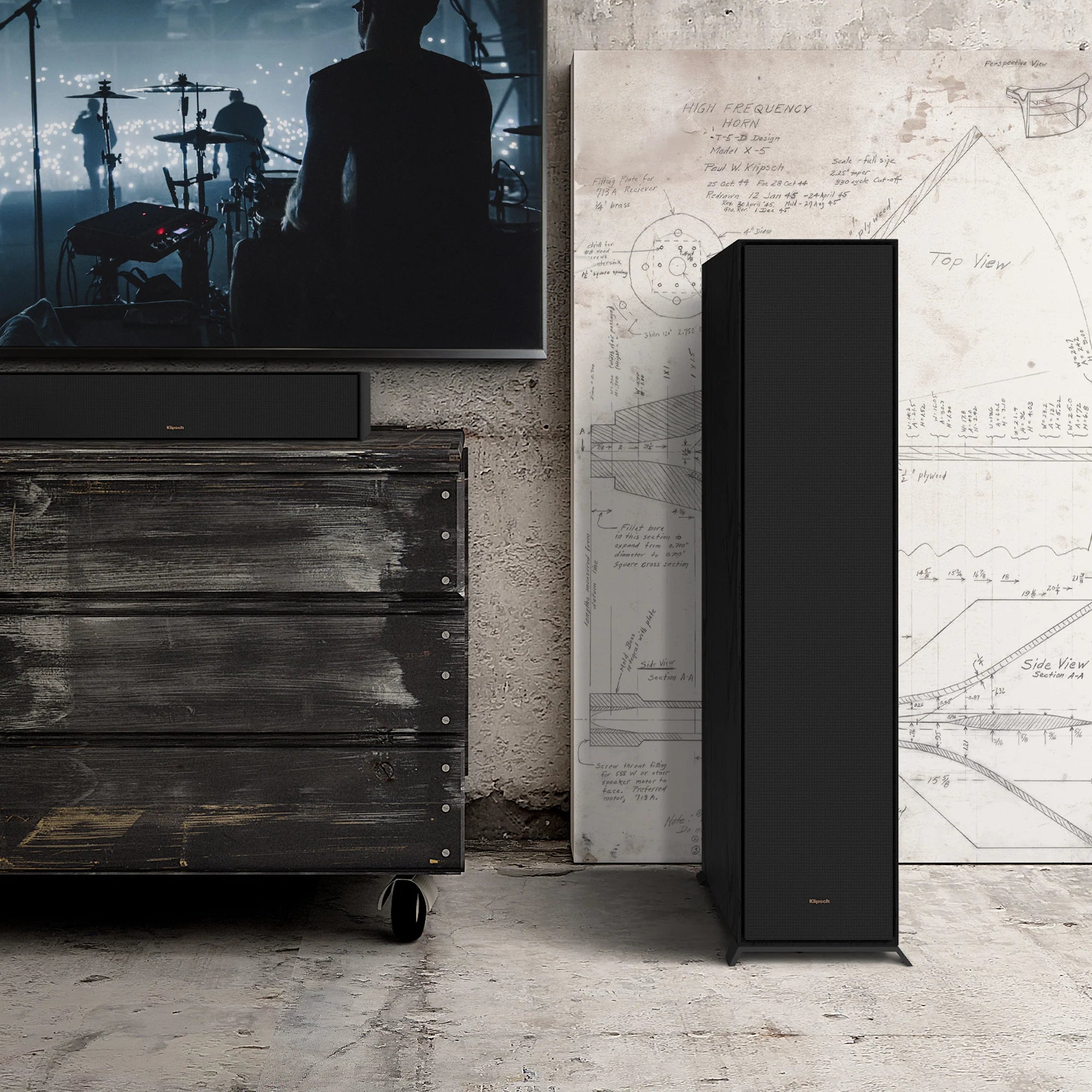 Boxă de podea Klipsch R-600F neagră, vedere frontală, grilaj textil montat, amplasată lângă mobilier TV.
