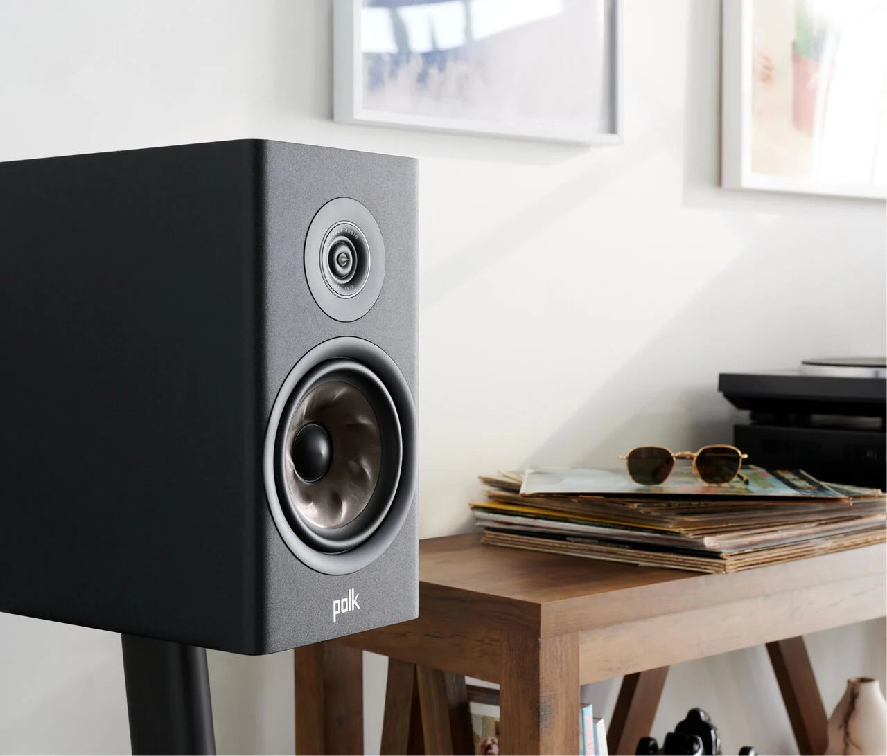 Boxa Polk Audio Reserve R100 neagră, vedere laterală, arătând difuzorul și tweeterul într-un mediu casnic.