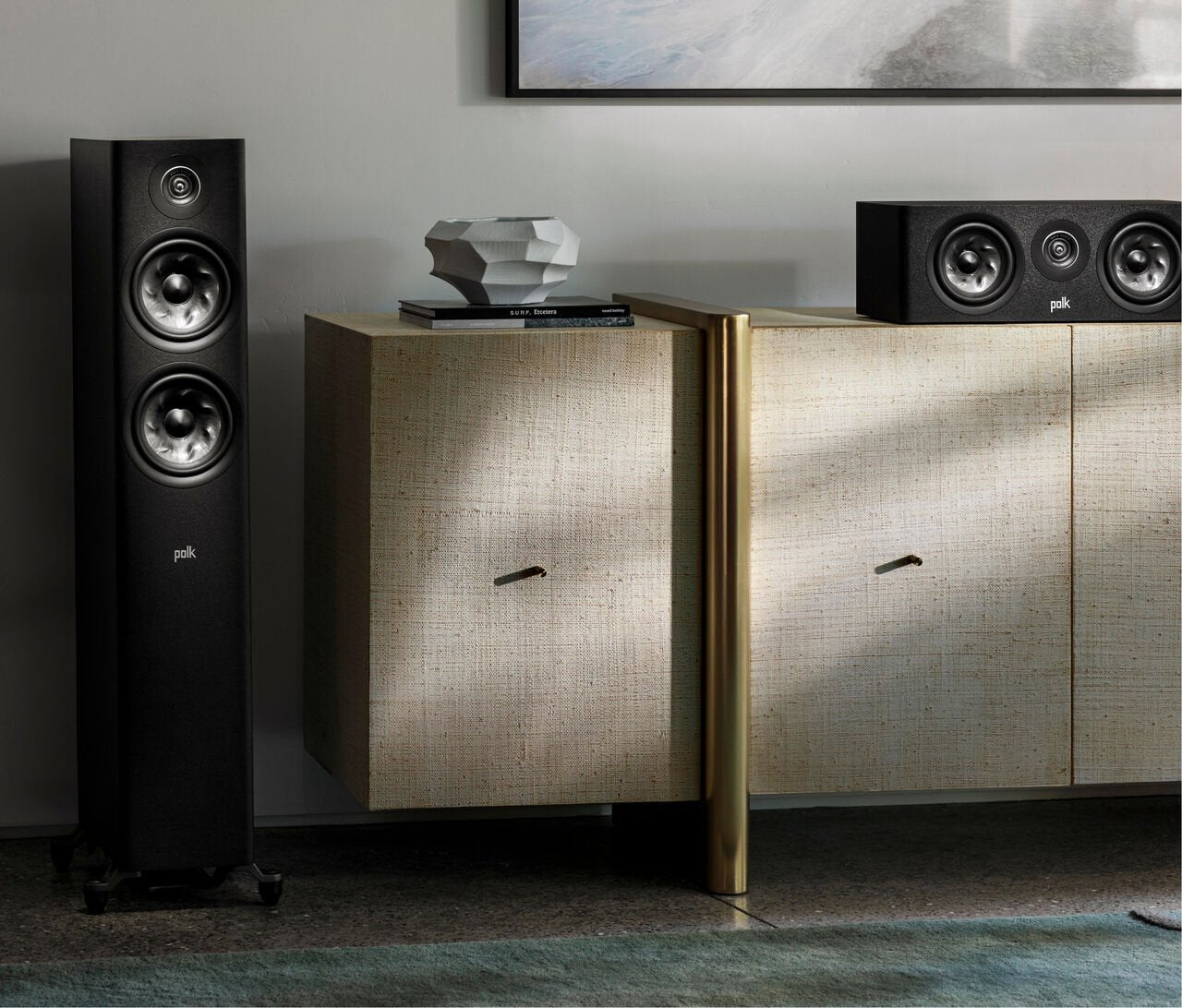 Polk Audio Reserve R300 Boxe centru negru, vedere frontală, amplasat pe un dulap în sufragerie. Două difuzoare mari și un tweeter central vizibile.