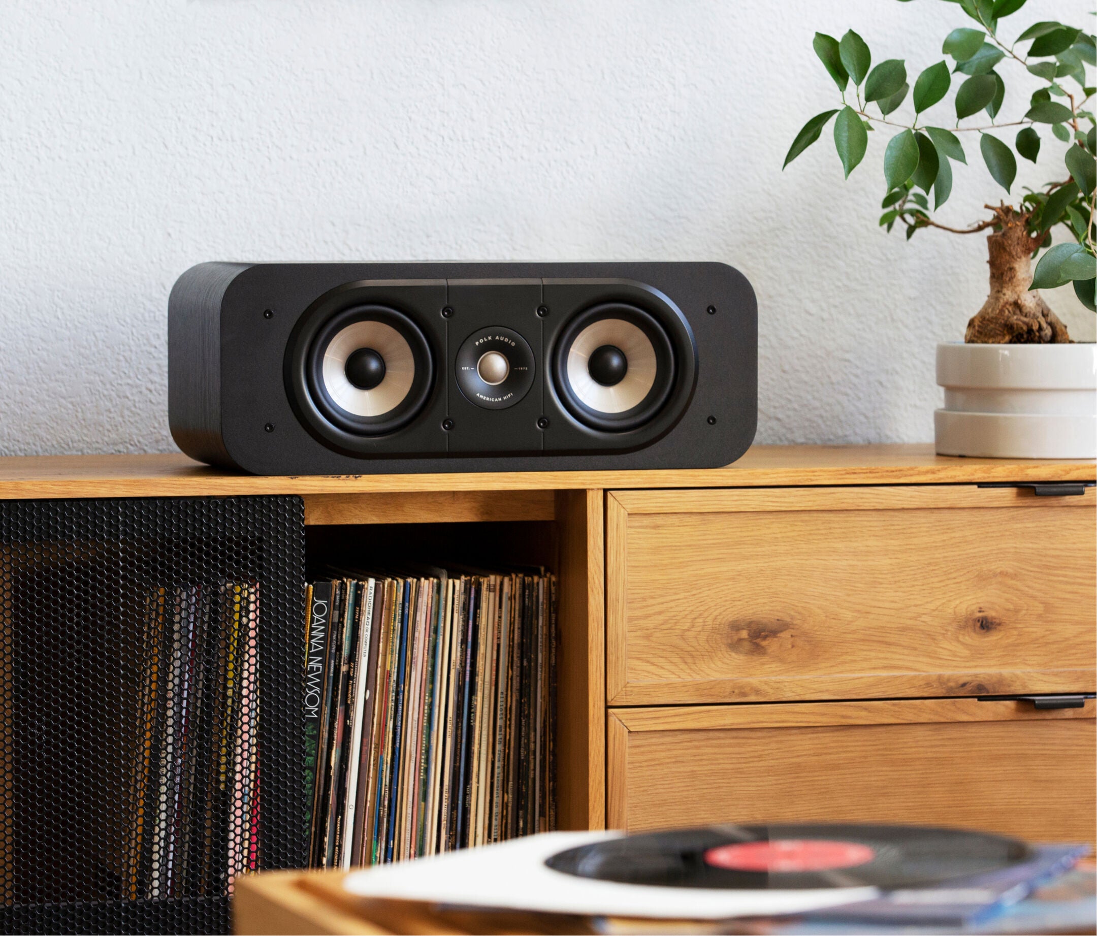 Boxa centru Polk Audio Signature Elite ES30 neagră, plasată pe un dulap de lemn, cu două difuzoare vizibile.