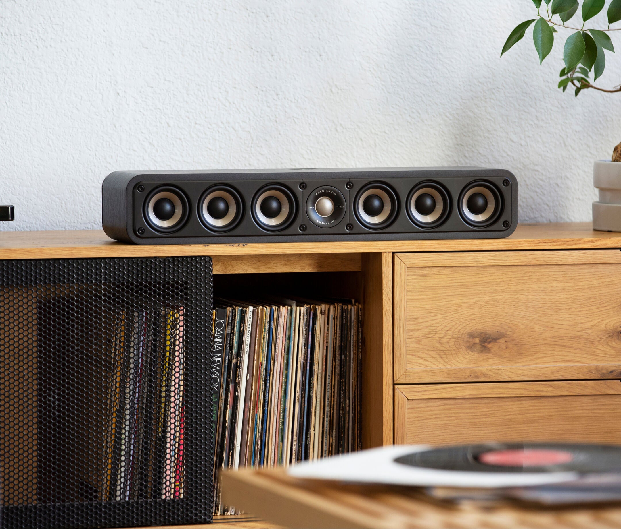 Boxa centru Polk Audio Signature Elite ES35, negru, amplasată pe un raft de lemn, cu șase difuzoare vizibile.