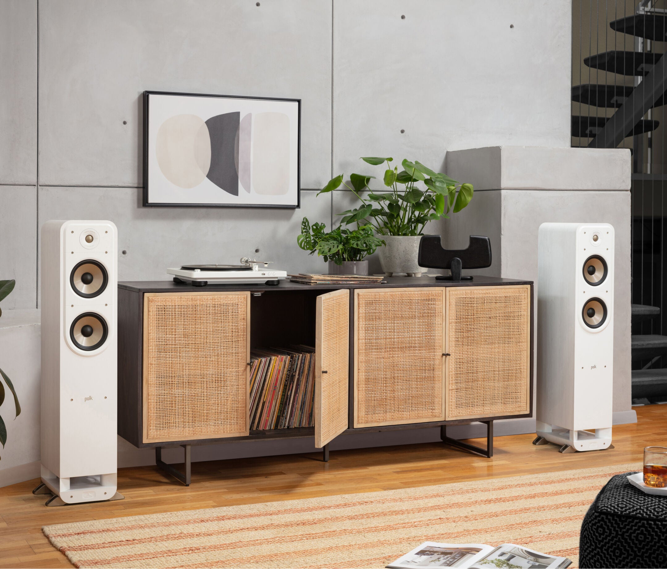 Boxe de podea Polk Audio Signature Elite ES55 albe, amplasate lângă un mobilier modern, cu două difuzoare vizibile.