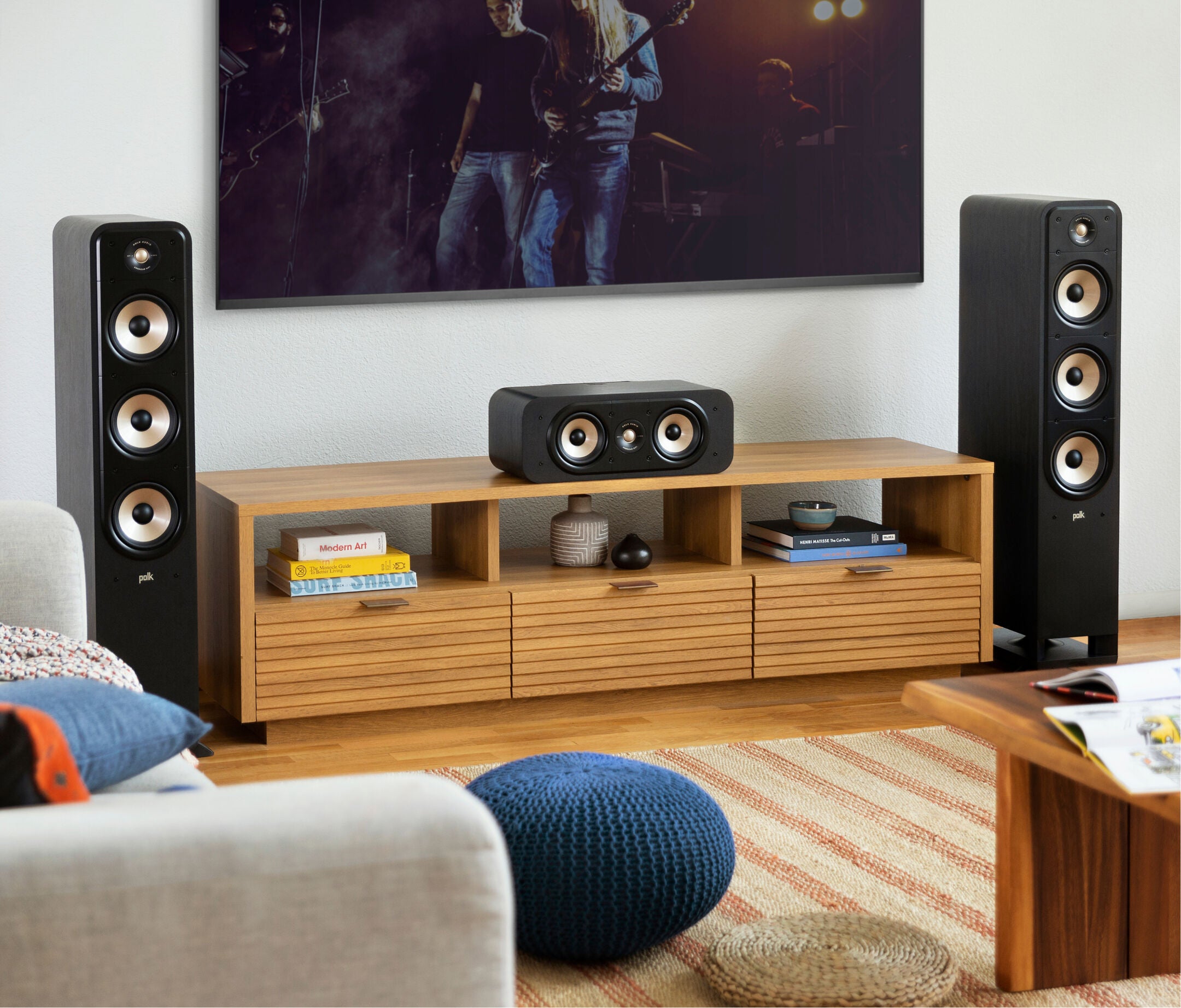 Boxe de podea Polk Audio Signature Elite ES60 negre, amplasate lângă un mobilier din lemn, într-un living.