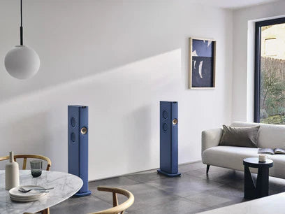 Boxe active KEF LS60 albastre, vedere frontală în cameră de zi, difuzoare Uni-Q și porturi vizibile.