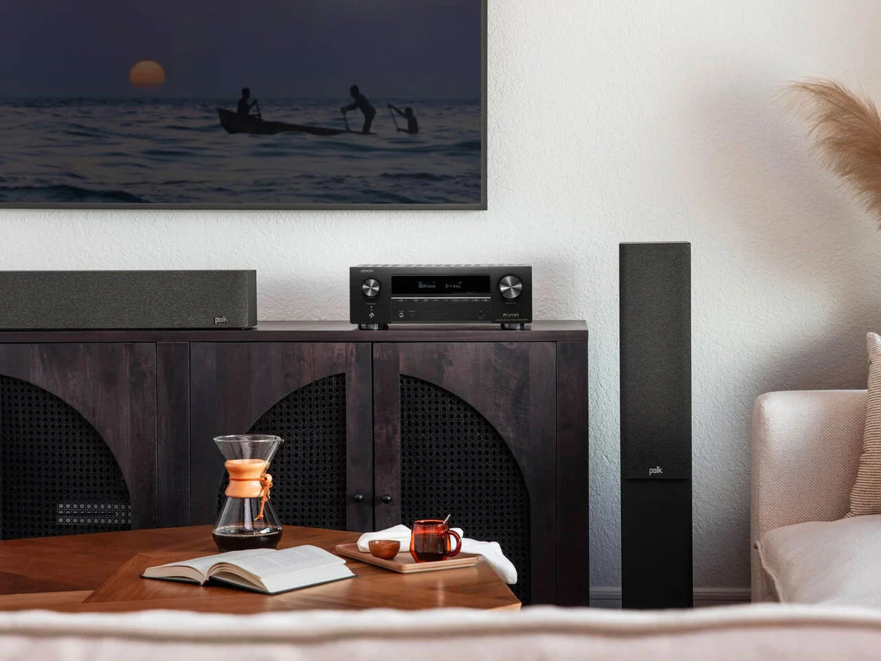 Denon AVR-X1700H Receiver AV negru, vedere frontală, amplasat pe un dulap, lângă boxe Polk Audio.