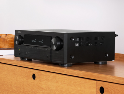 Receiver AV Denon AVR-X1800H DAB, vedere laterală stânga, culoare neagră, afișaj activ pe suport lemn.