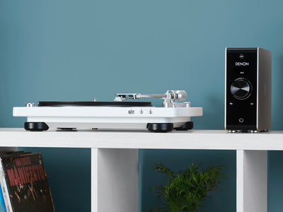 Pickup Denon DP-450USB alb, vedere laterală, port USB frontal și braț vizibil, amplificator alături.