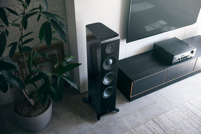 Boxă de podea Yamaha NS-2000A neagră, vedere de sus, lângă mobilier TV și plantă. Prezintă trei difuzoare mari.