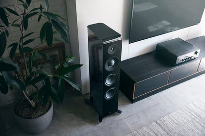 Boxă de podea Yamaha NS-2000A neagră, vedere de sus, lângă mobilier TV și plantă. Prezintă trei difuzoare mari.