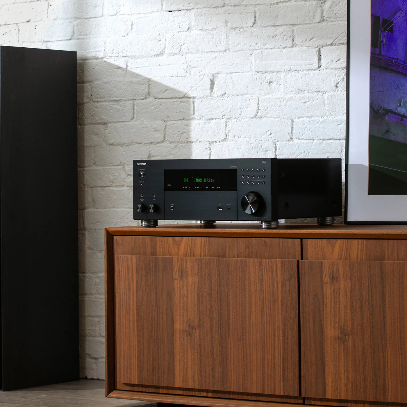 Receiver AV Onkyo TX-RZ30 negru, vedere frontală cu afișaj DTS:X, lângă boxă de podea verticală.