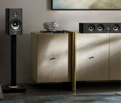 Boxa Polk Audio Reserve R200 neagră, amplasată pe suport, lângă o unitate centrală cu patru difuzoare.