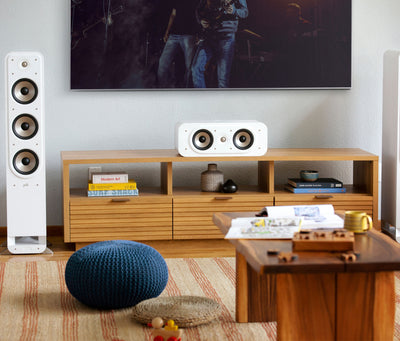 Boxa centru Polk Audio Signature Elite ES30 albă, amplasată pe un suport din lemn, lângă un televizor.