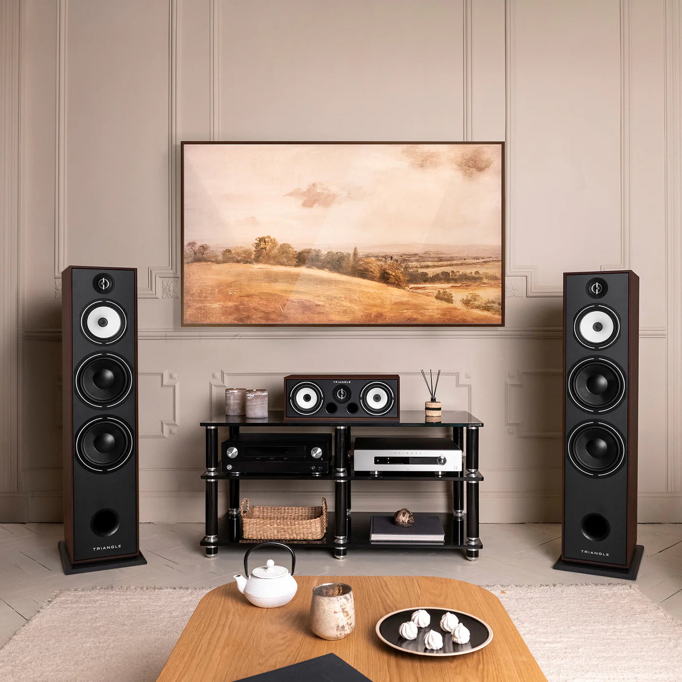 Boxe de podea Triangle Borea BR10, culoare nuc, amplasate într-un living modern, alături de un sistem audio complet.