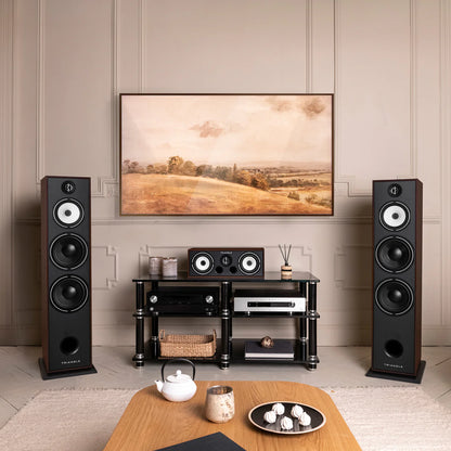 Boxe de podea Triangle Borea BR10, culoare nuc, amplasate într-un living modern, alături de un sistem audio complet.